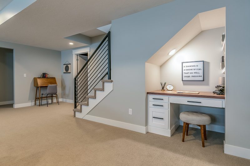 basement rec room with home office desk underneath the stairs